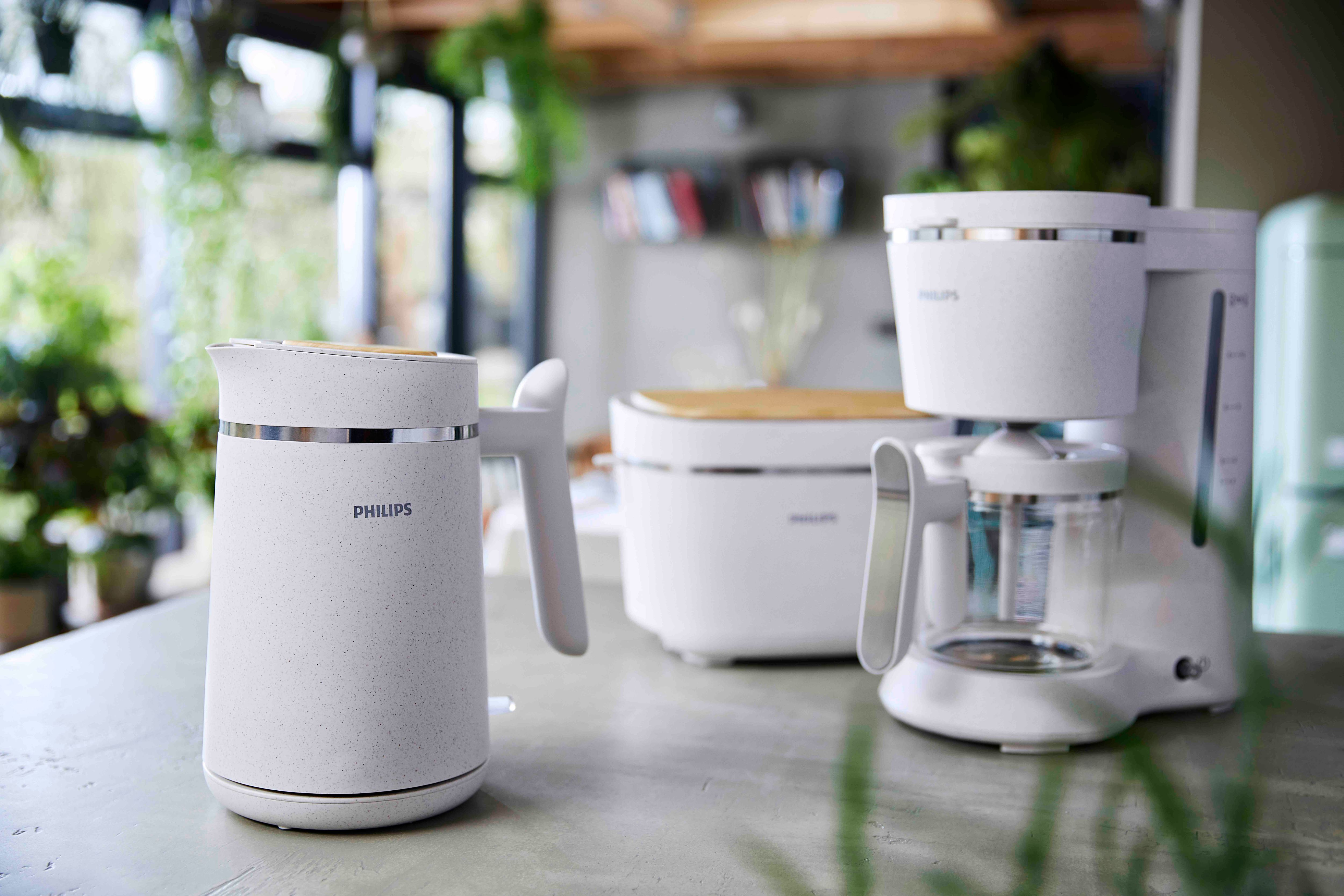 Kitchen appliances: white kettle, toaster, and coffee maker on a gray counter.