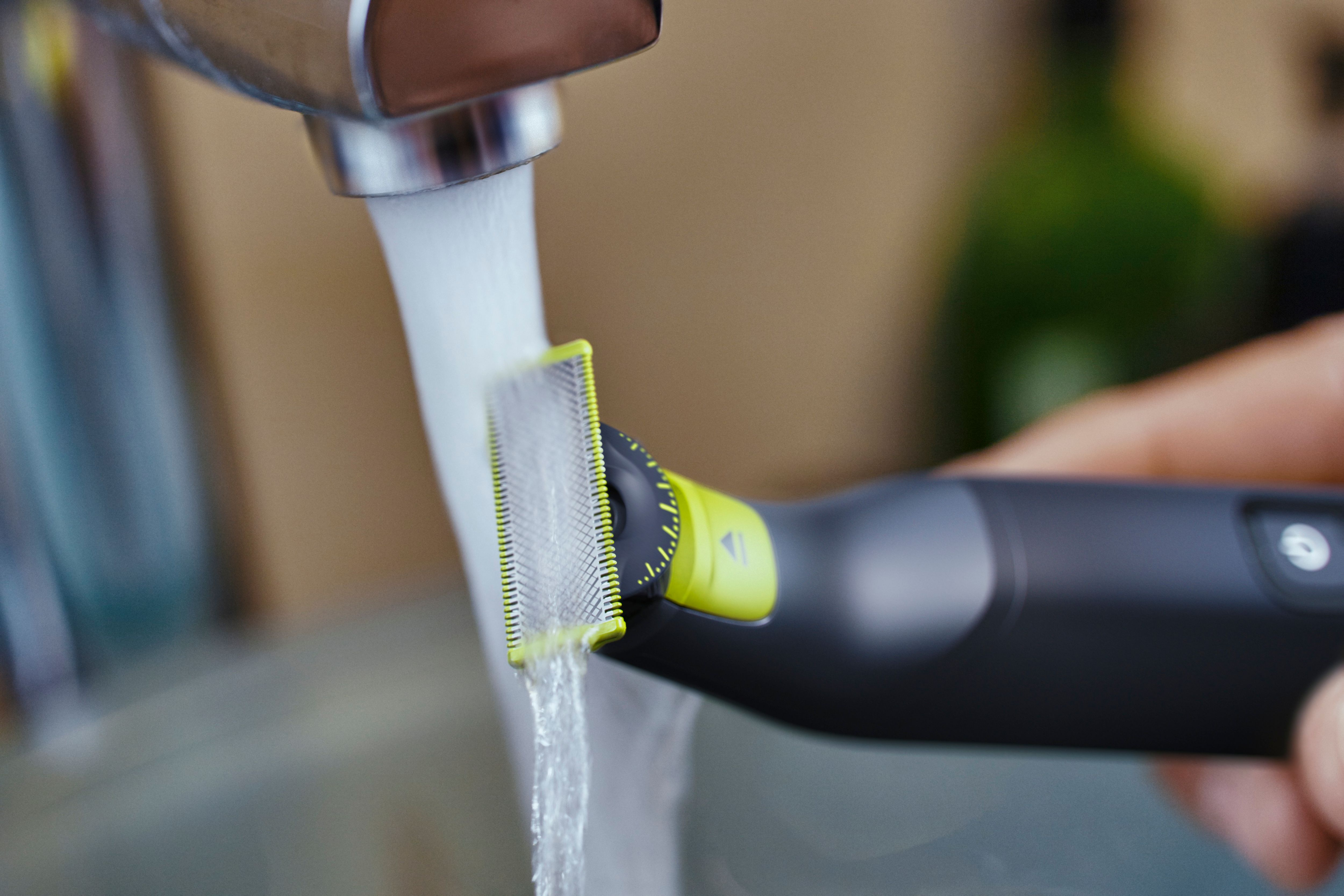 Close-up van een Philips OneBlade die wordt afgespoeld onder stromend water.