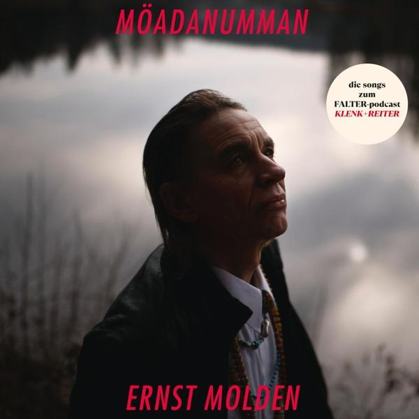 Albumcover mit einem Mann, der nach oben schaut, Text oben und unten, auf verschwommenem Hintergrund.