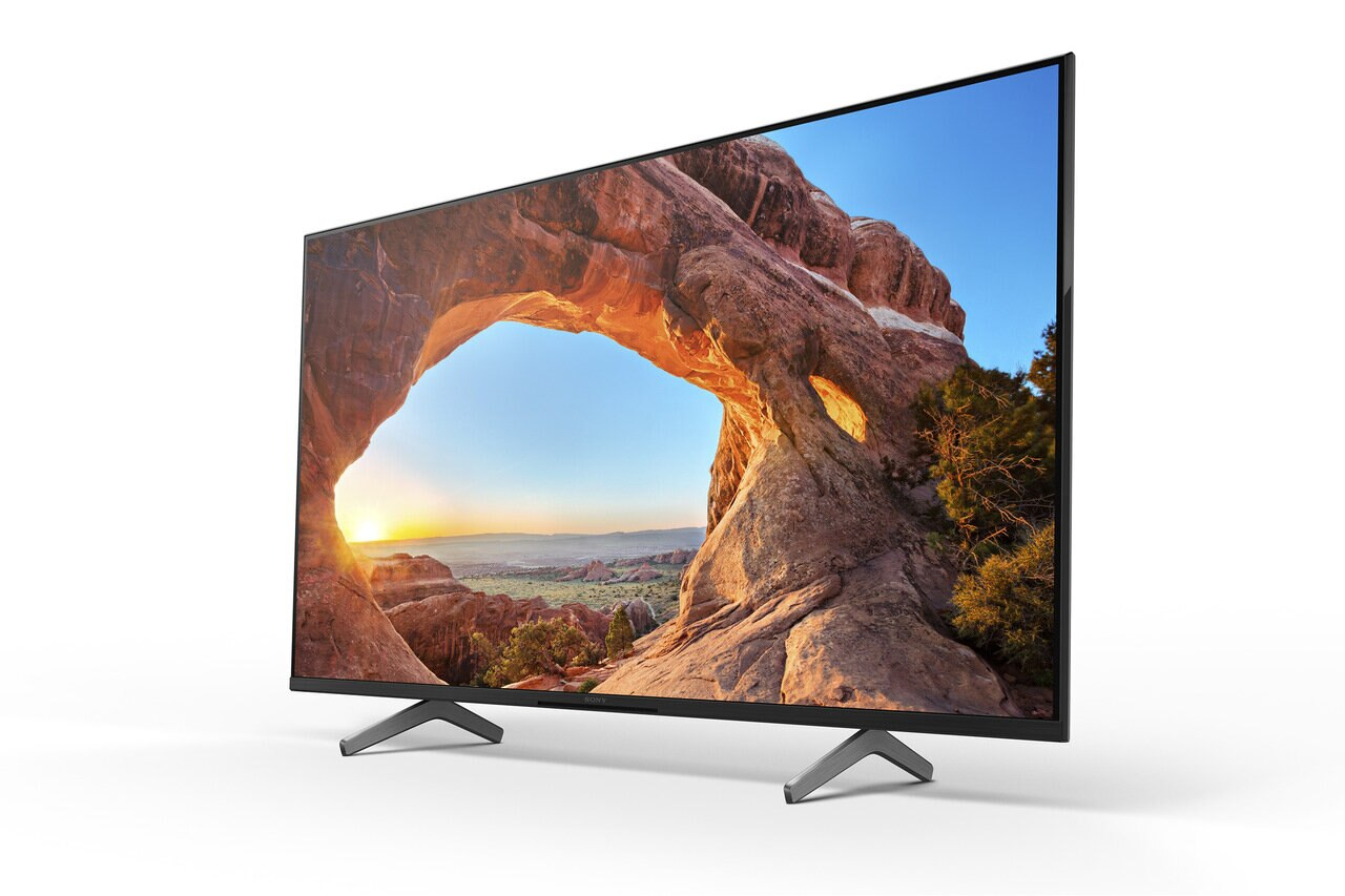 Telewizor wyświetlający krajobraz łukowy, na białym tle, z ukośnymi nogami.