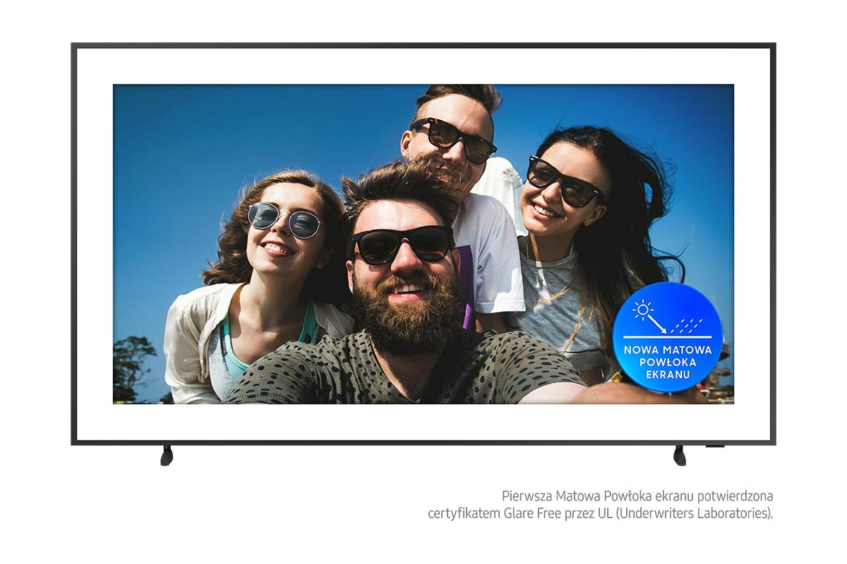 Grupa osób robiących sobie selfie na plaży z czystym, błękitnym niebem.