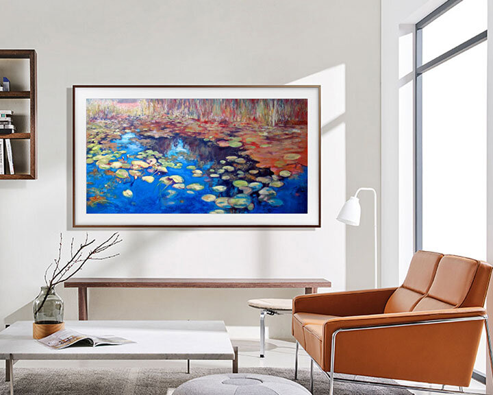Oprawione dzieło sztuki z liliami wodnymi, brązowa rama, na białej ścianie, ze skórzanym fotelem i stolikiem kawowym.