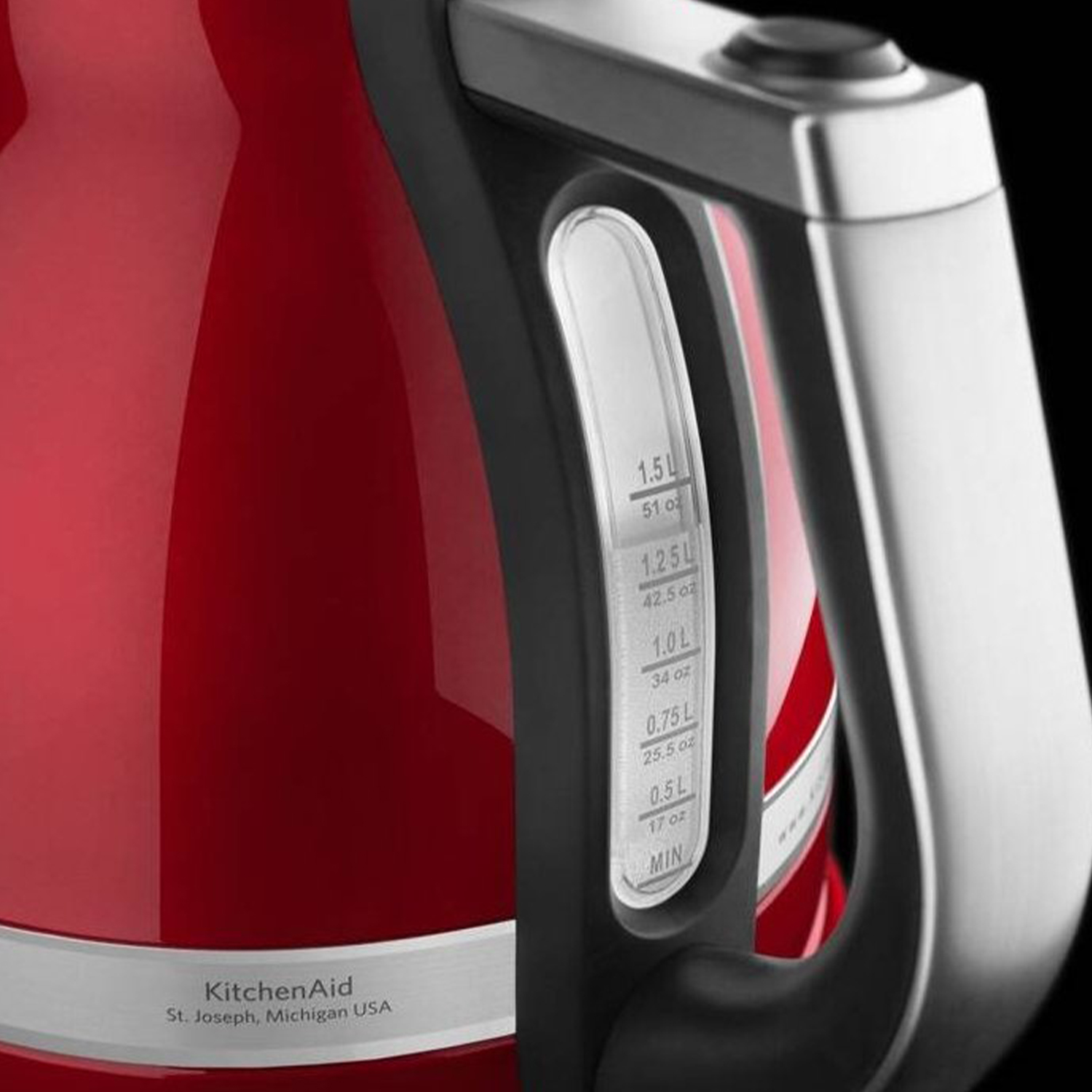 Primo piano di un bollitore KitchenAid rosso. Mostra indicatore livello acqua e manico nero.