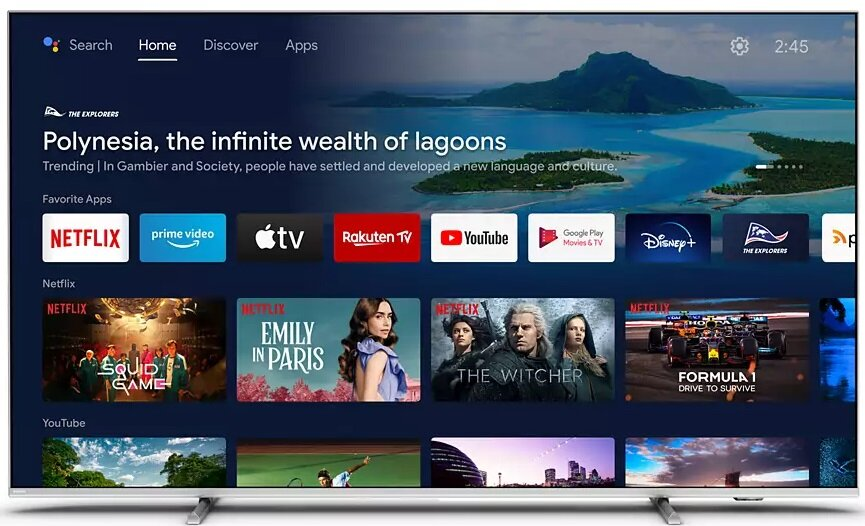 Ekran TV wyświetla ekran główny z ikonami aplikacji, krajobraz górski i wodny.