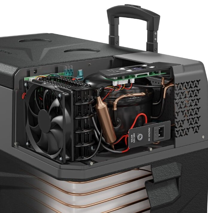 Otwarty widok przenośnej lodówki, pokazujący elementy wewnętrzne, takie jak wentylator, sprężarka i rury chłodzące, z uchwytem.