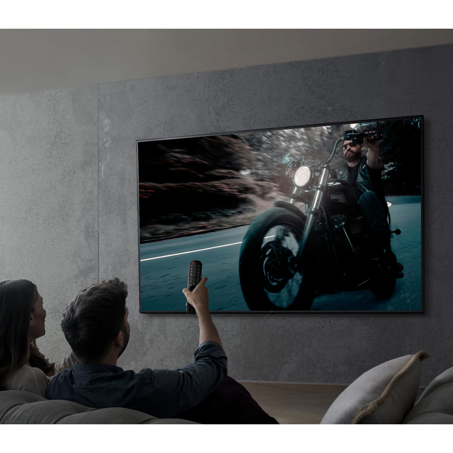 Couple regardant la télévision montrant un motard. La femme à gauche, l'homme à droite.