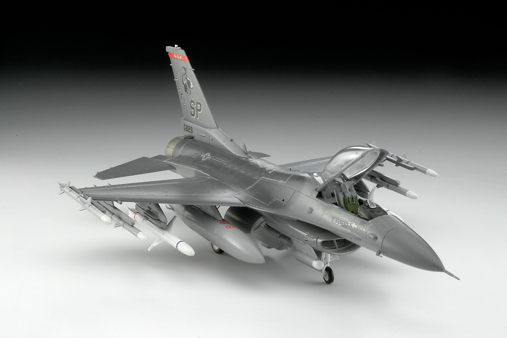 Modell eines grauen Militärjets, Flügel ausgebreitet. Weißer Hintergrund, detailliertes Design.