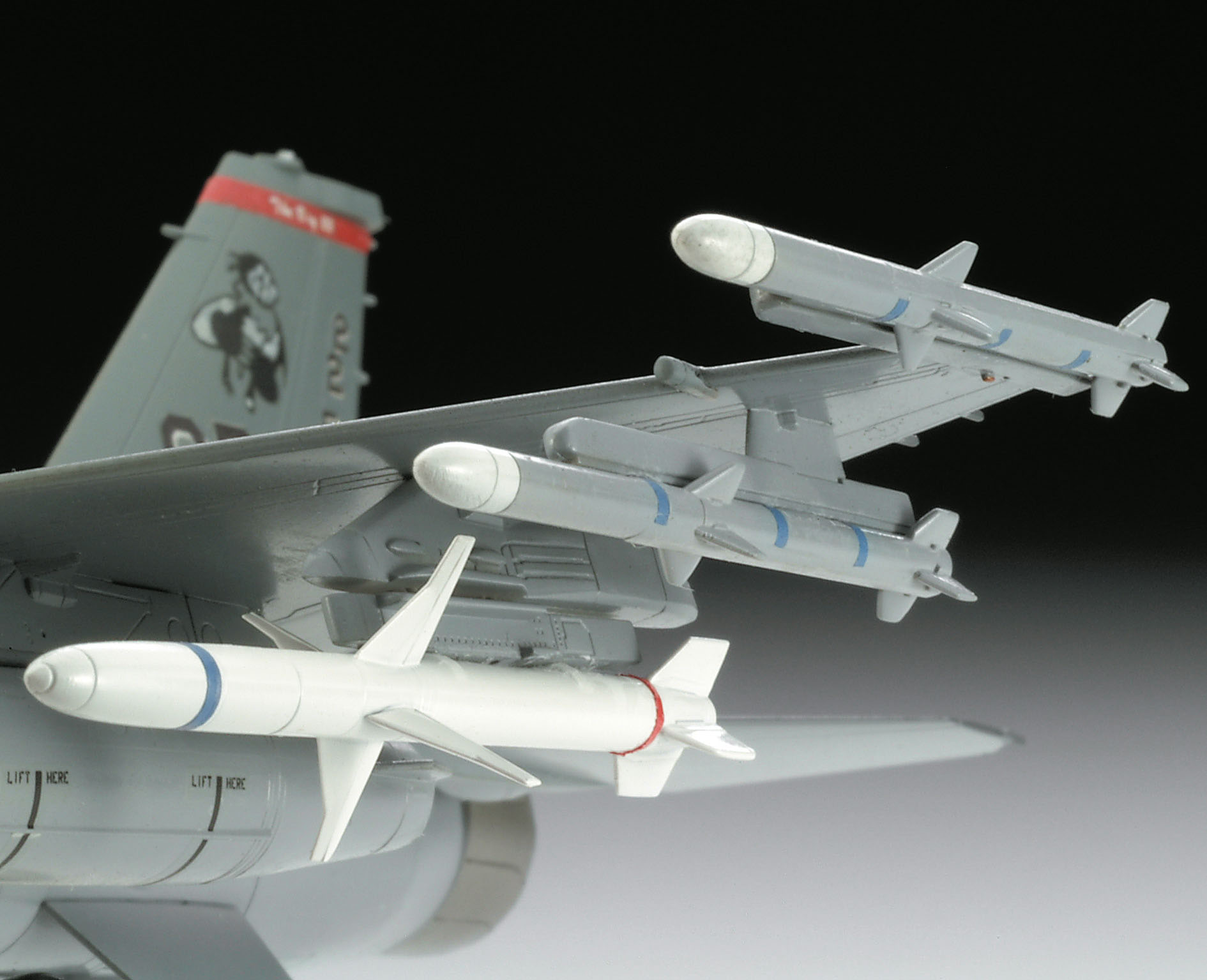 Nahaufnahme eines Modellflugzeugflügels mit angebrachten Raketen, graue und weiße Farben sichtbar.