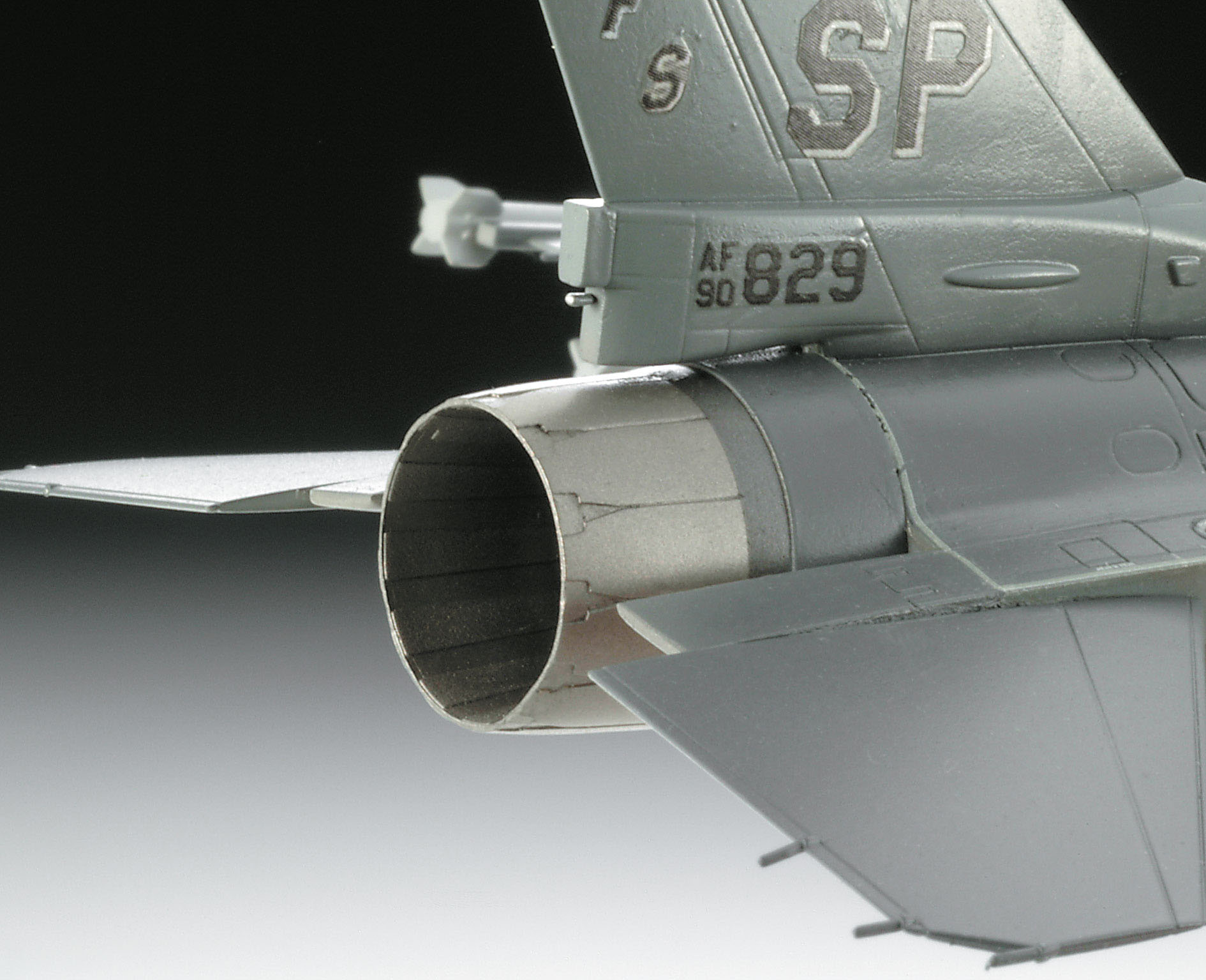 Nahaufnahme des Hecks eines grauen Militärflugzeugs, das den Auspuff zeigt.