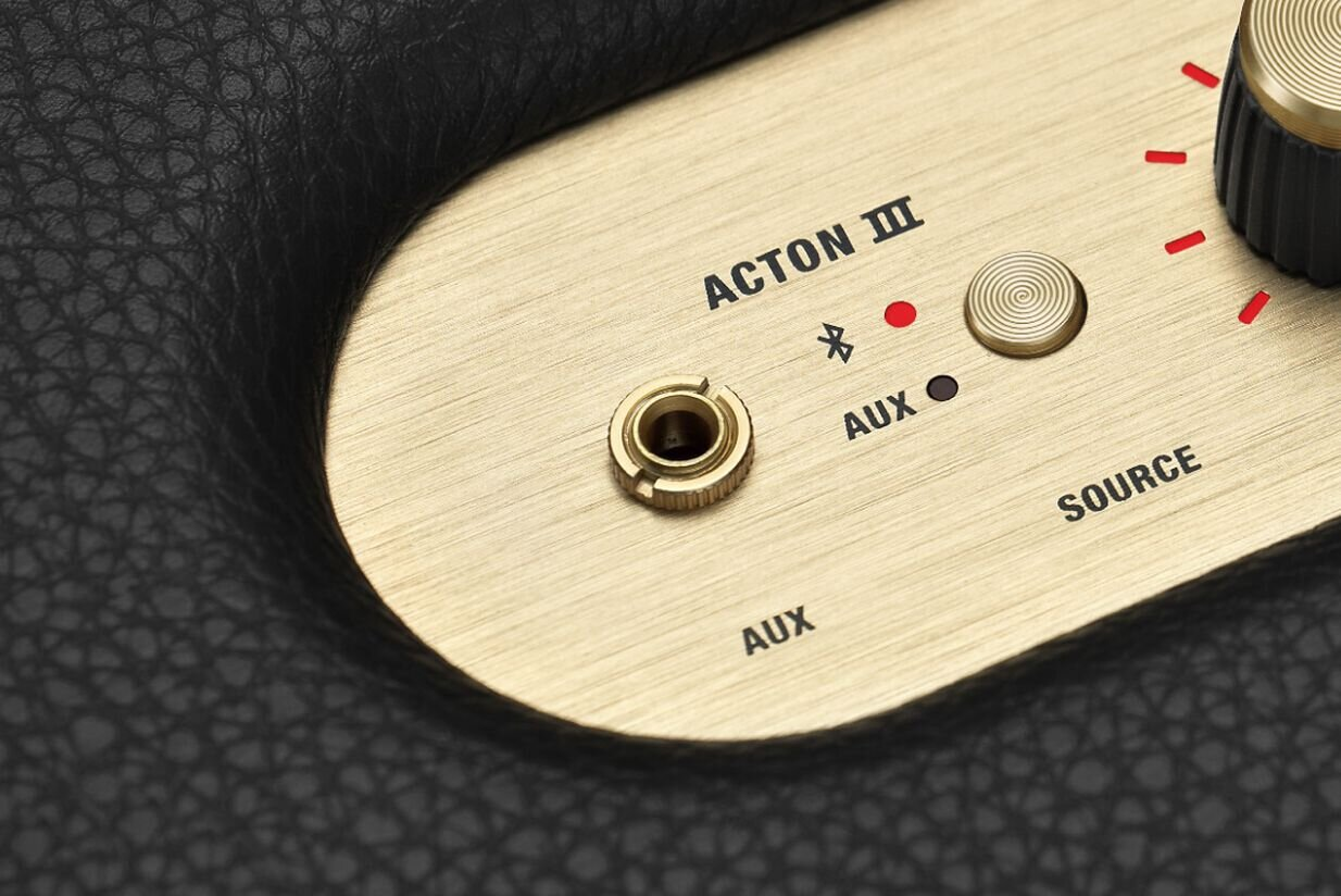 Zbliżenie panelu audio w kolorze mosiądzu z napisami Acton III, Bluetooth i AUX.