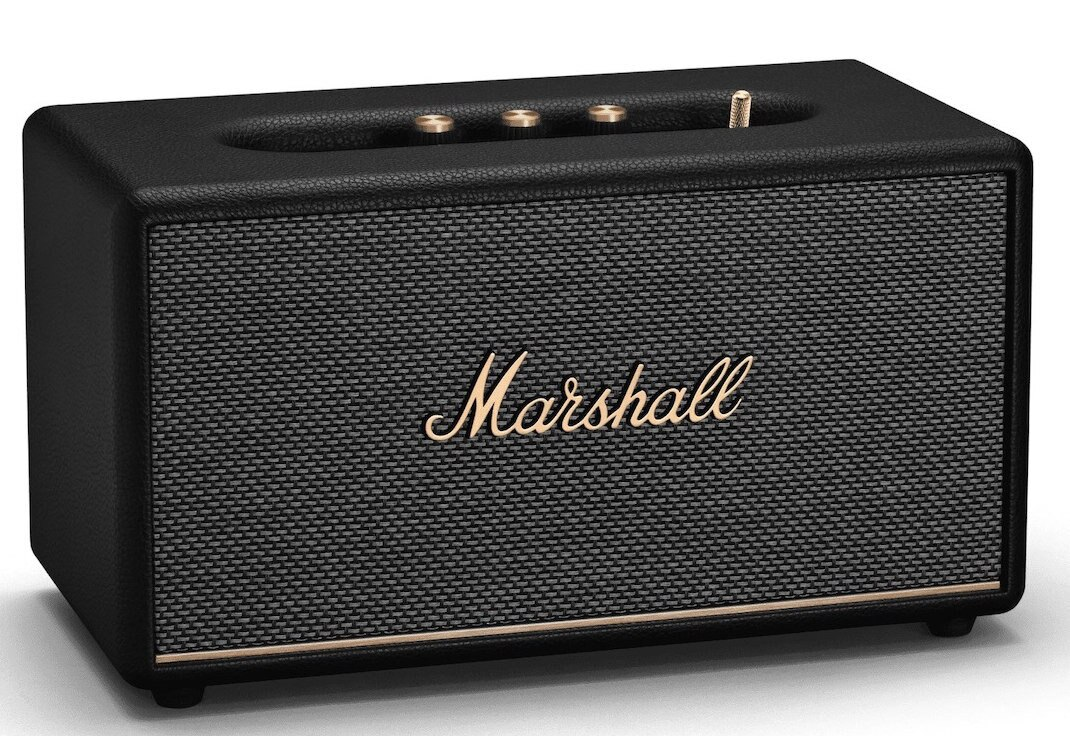 Czarny głośnik Marshall ze złotymi literami i szarą siatką z przodu. Głośnik stoi na białej powierzchni.