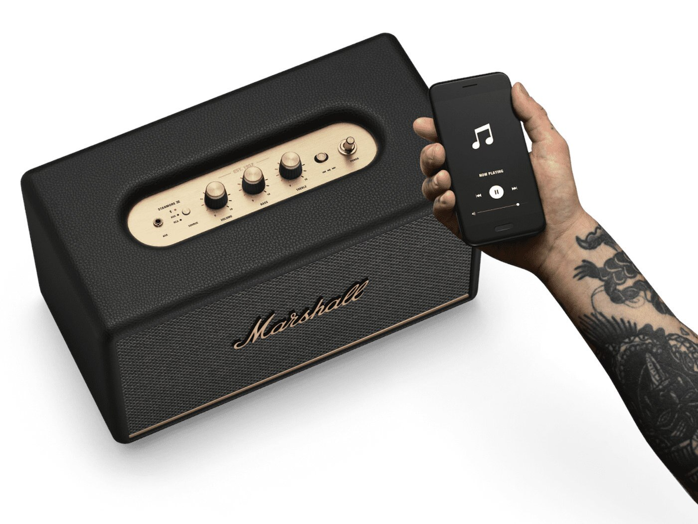 Ręka trzymająca czarny smartfon odtwarzający muzykę, podłączony do głośnika Marshall.