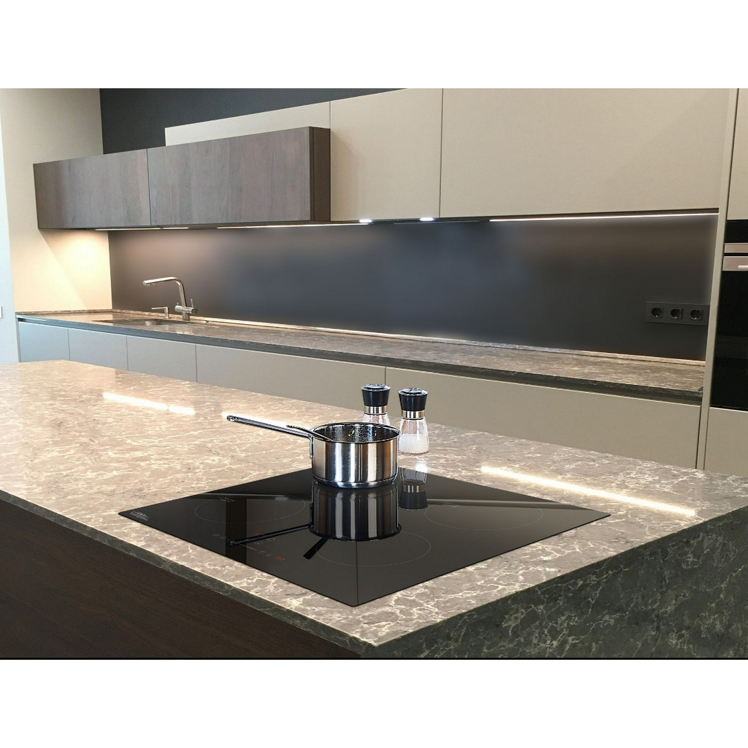 A kitchen with a stone countertop, an induction hob, and a pot. Overhead cabinets and a black backsplash.