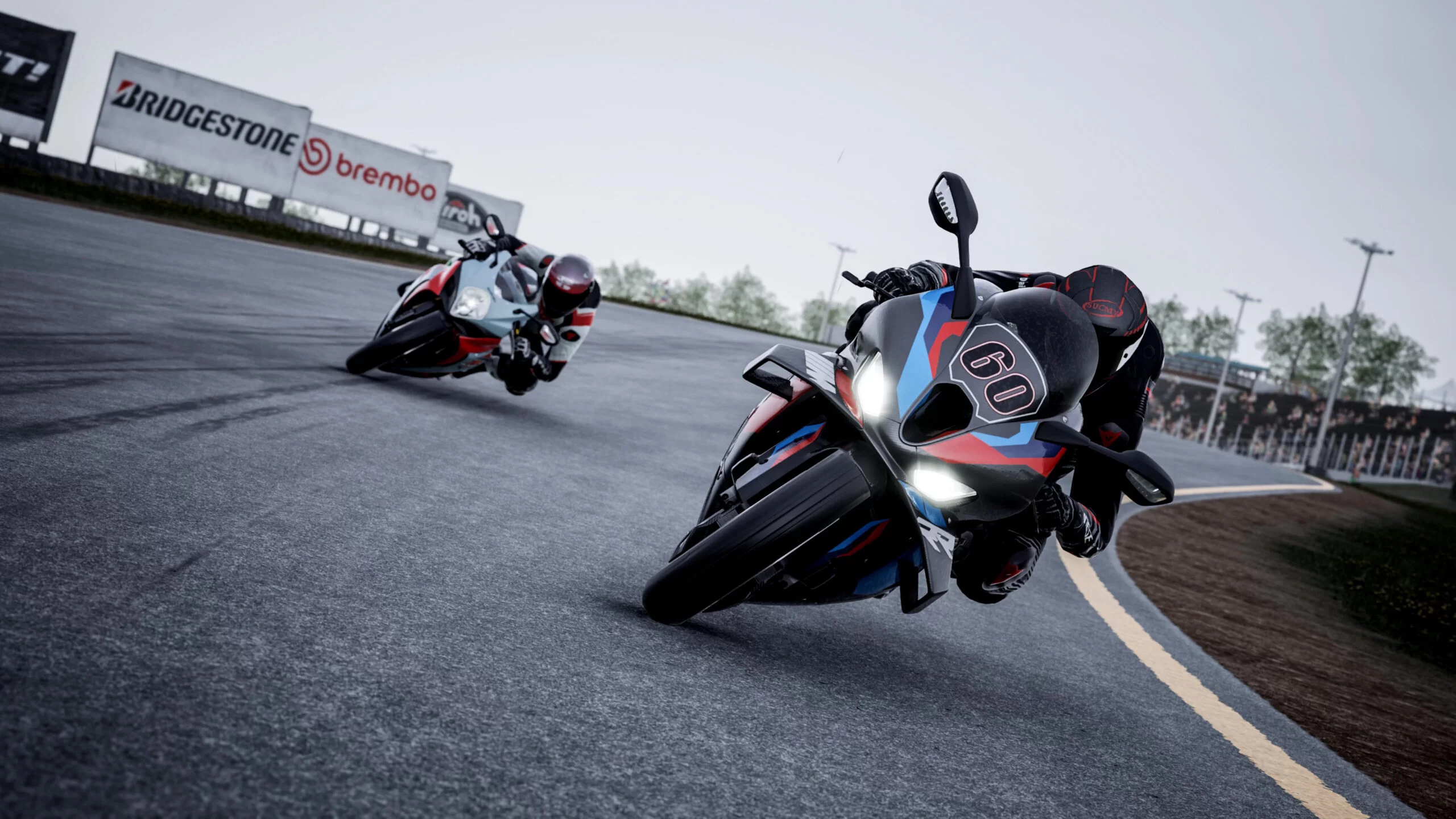 Due moto che corrono su una pista, con un cartello Bridgestone e uno sfondo sfocato.