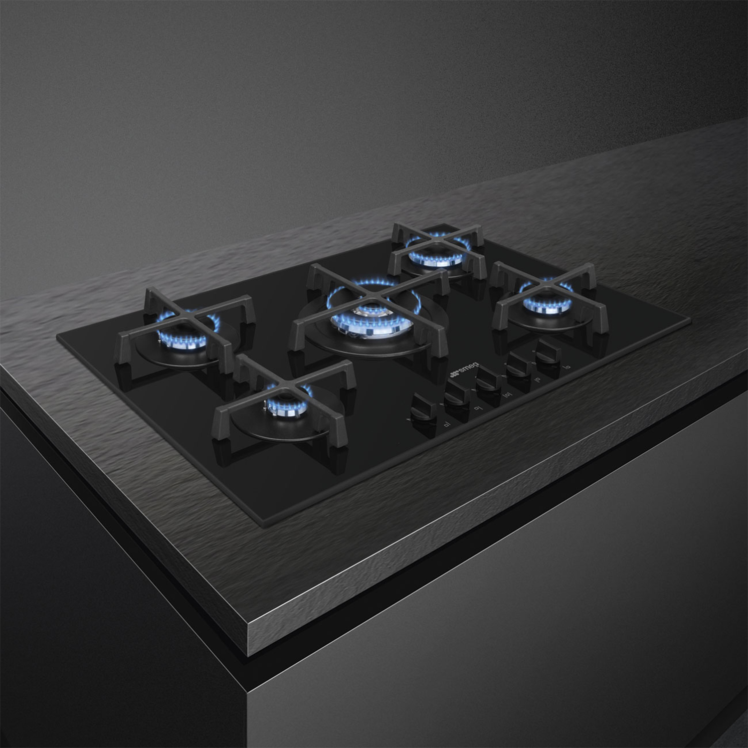 Piano cottura nero con cinque fiamme blu accese. Elettrodomestico da cucina elegante e moderno.