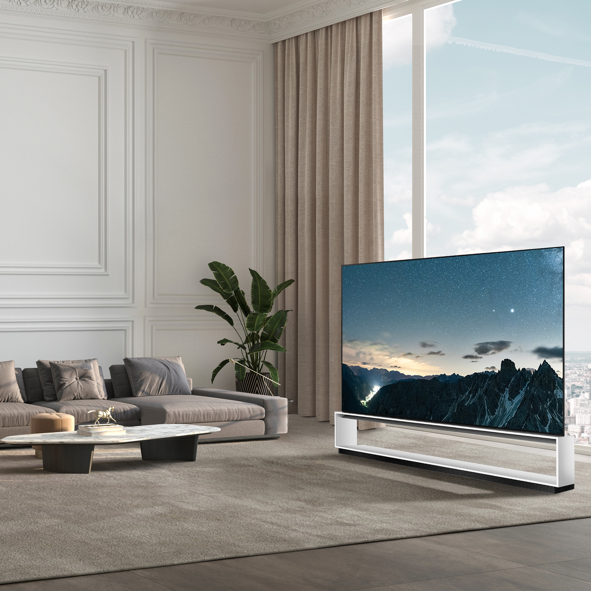 Salón moderno con un televisor grande que muestra una escena nocturna, sofá gris y ventana grande.