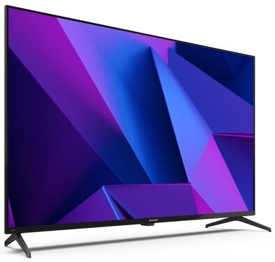 Telewizor z płaskim ekranem wyświetla fioletowe i niebieskie kształty geometryczne na białym tle.