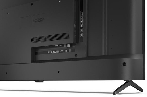 Zbliżenie na tył czarnego telewizora, pokazujące porty, połączenia i stojak. Telewizor jest na białym tle.