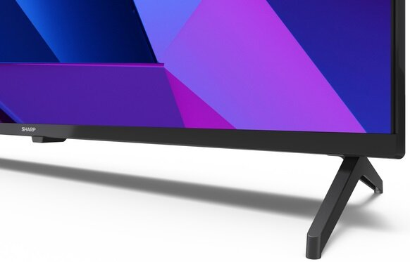 Ekran telewizora z kolorowym obrazem, czarną ramką i nóżkami na białym tle.