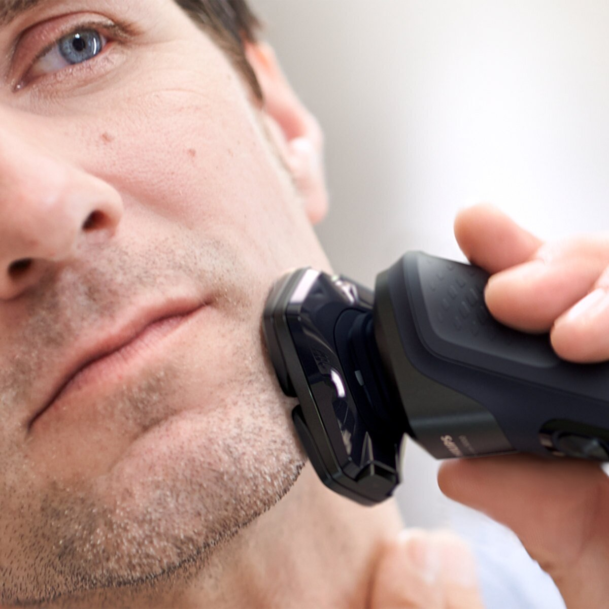 Mężczyzna goli brodę czarną golarką elektryczną Philips.