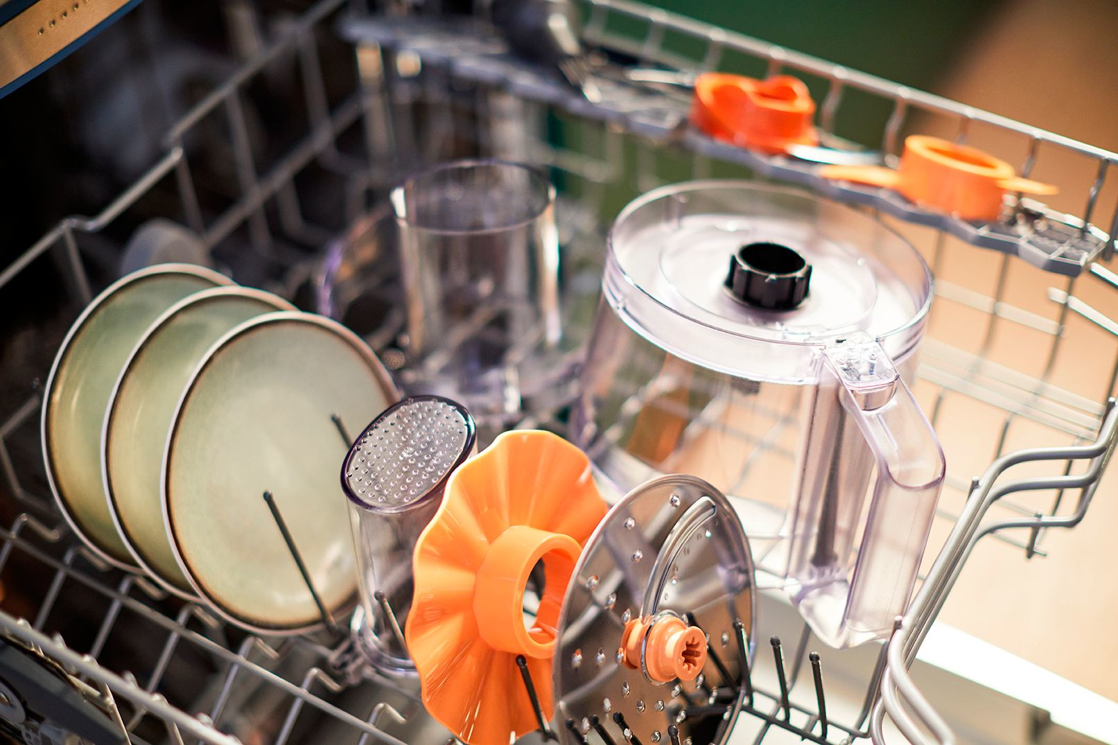 Dishwasher with plates, glasses, and various kitchen appliance parts inside.