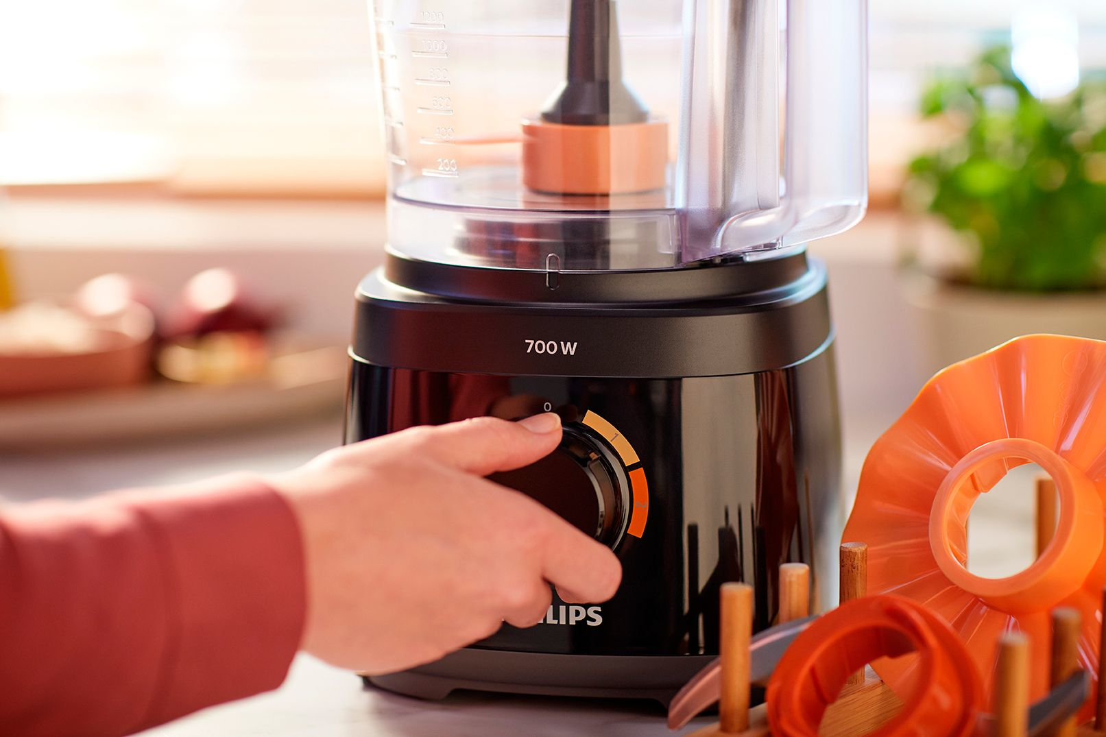 A person using a food processor, with the power dial visible and other parts.