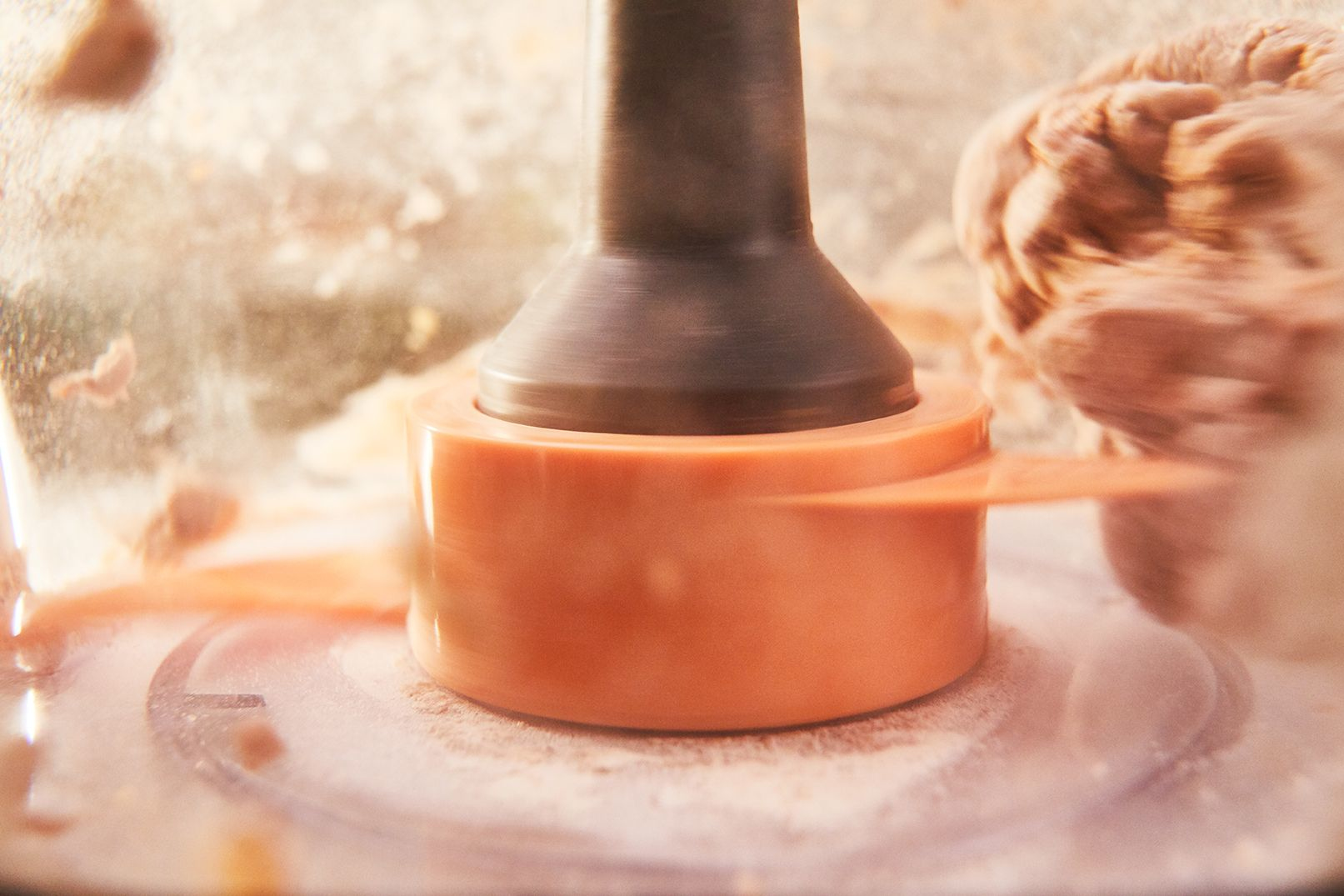 Food processor in operation. The blade is orange and the food is light brown.