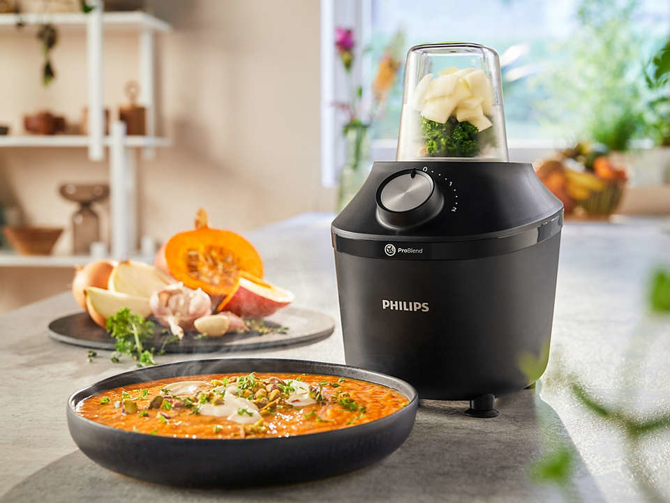 Blender with ingredients inside, with a bowl of soup.