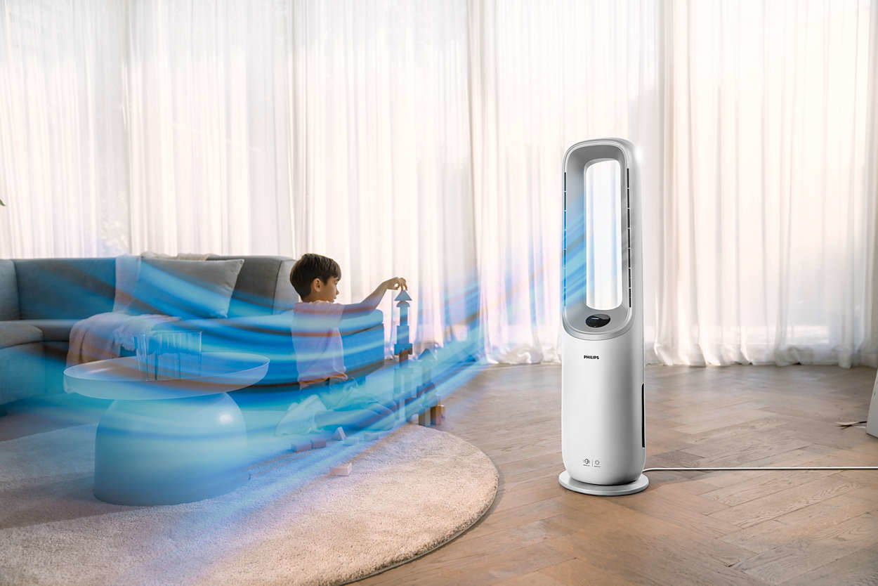 A living room with a boy, a fan, and a coffee table. The fan is blowing blue air.