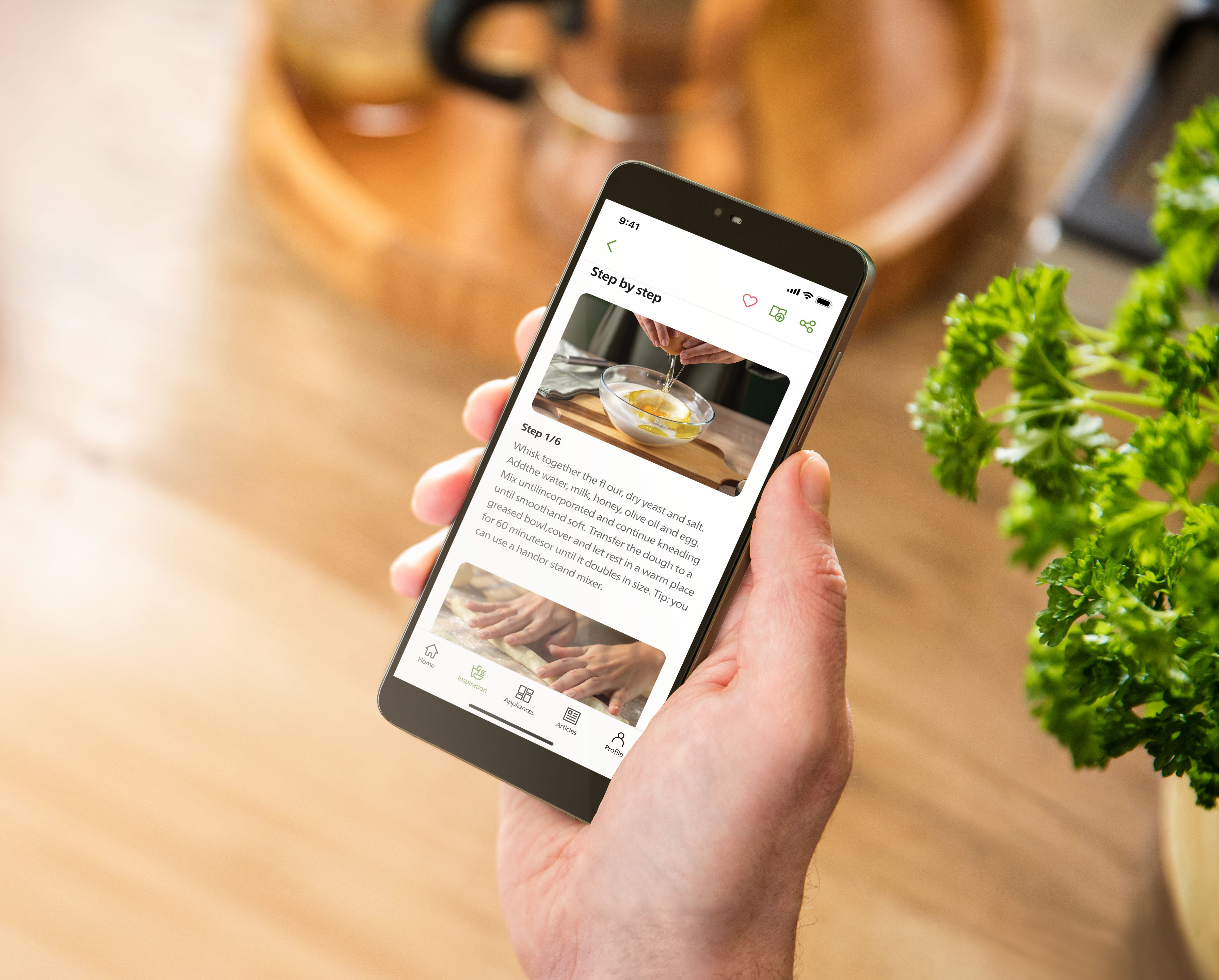 A hand holds a phone showing a recipe app with step-by-step instructions.