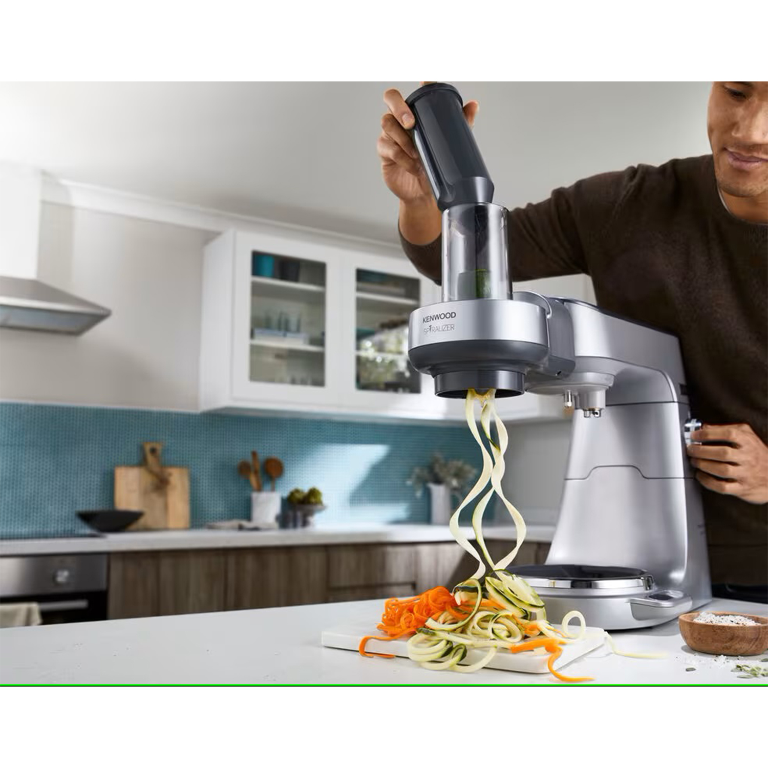 Un uomo usa un robot da cucina Kenwood per creare verdure a spirale.