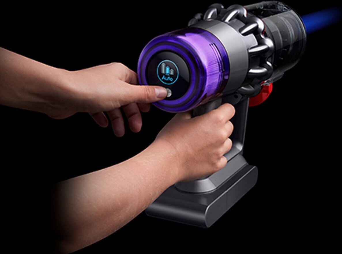 Ręka obsługuje bezprzewodowy odkurzacz Dyson. Przycisk zasilania jest wciśnięty, pokazując tryb Auto.