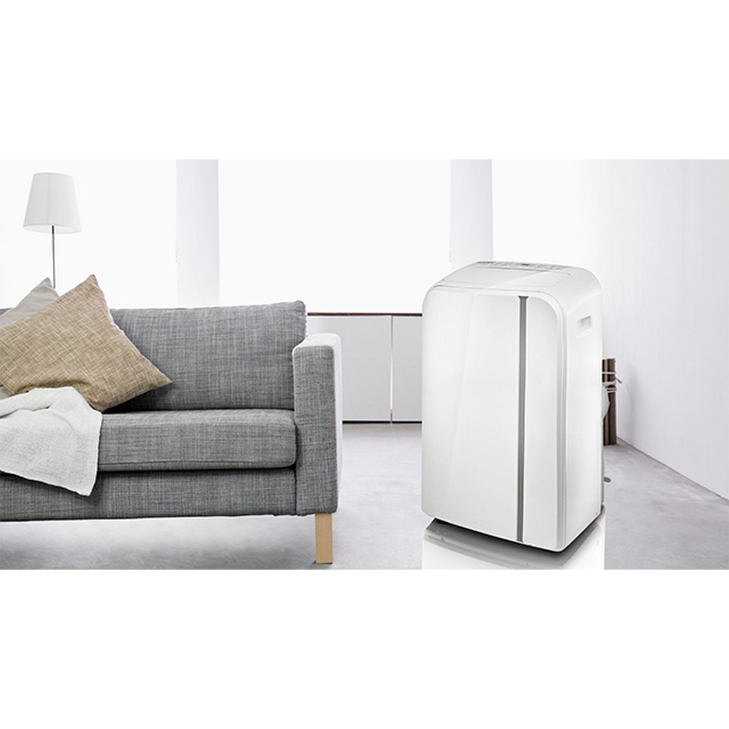 A white portable air conditioner next to a gray sofa in a bright room.