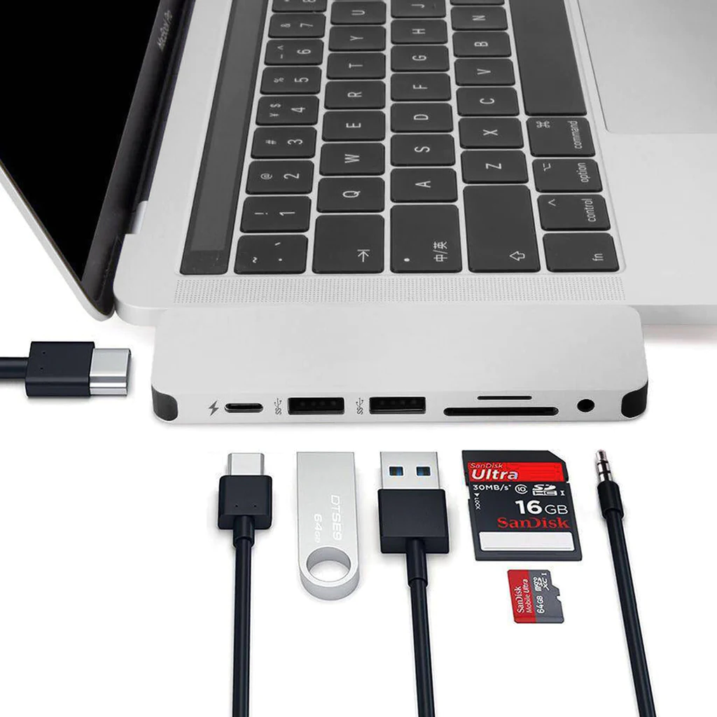 Un portátil con un hub conectado y varios accesorios: dispositivos USB, tarjeta SD y USB-C.