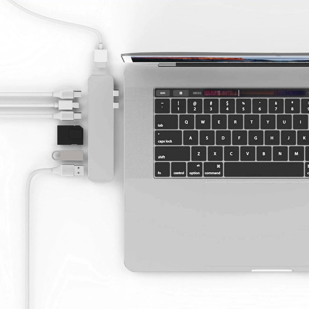 Un concentrador USB-C con varios puertos conectado a una computadora portátil. Un ratón está al lado.