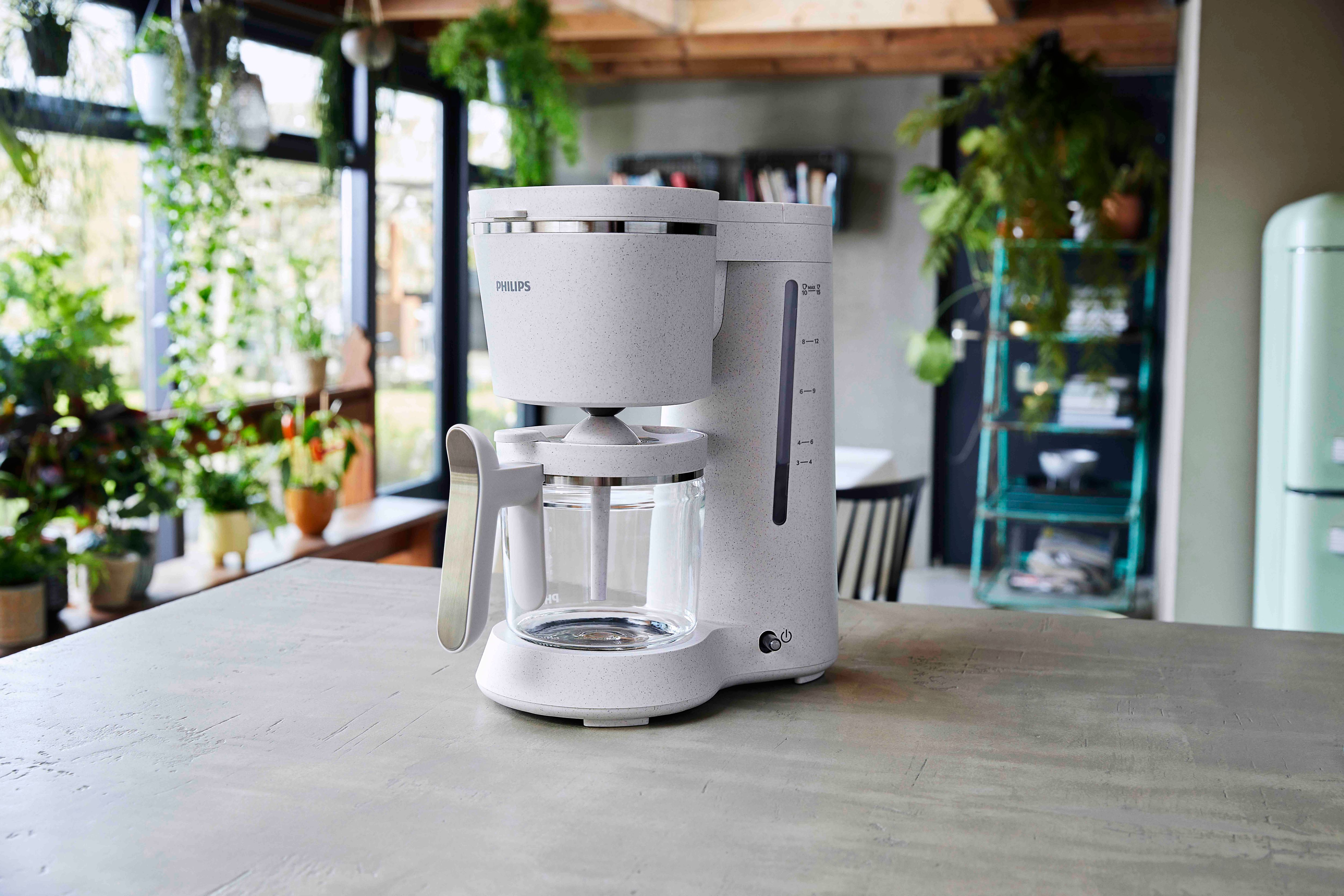 A white Philips coffee maker with a glass carafe, on a countertop in a kitchen setting.
