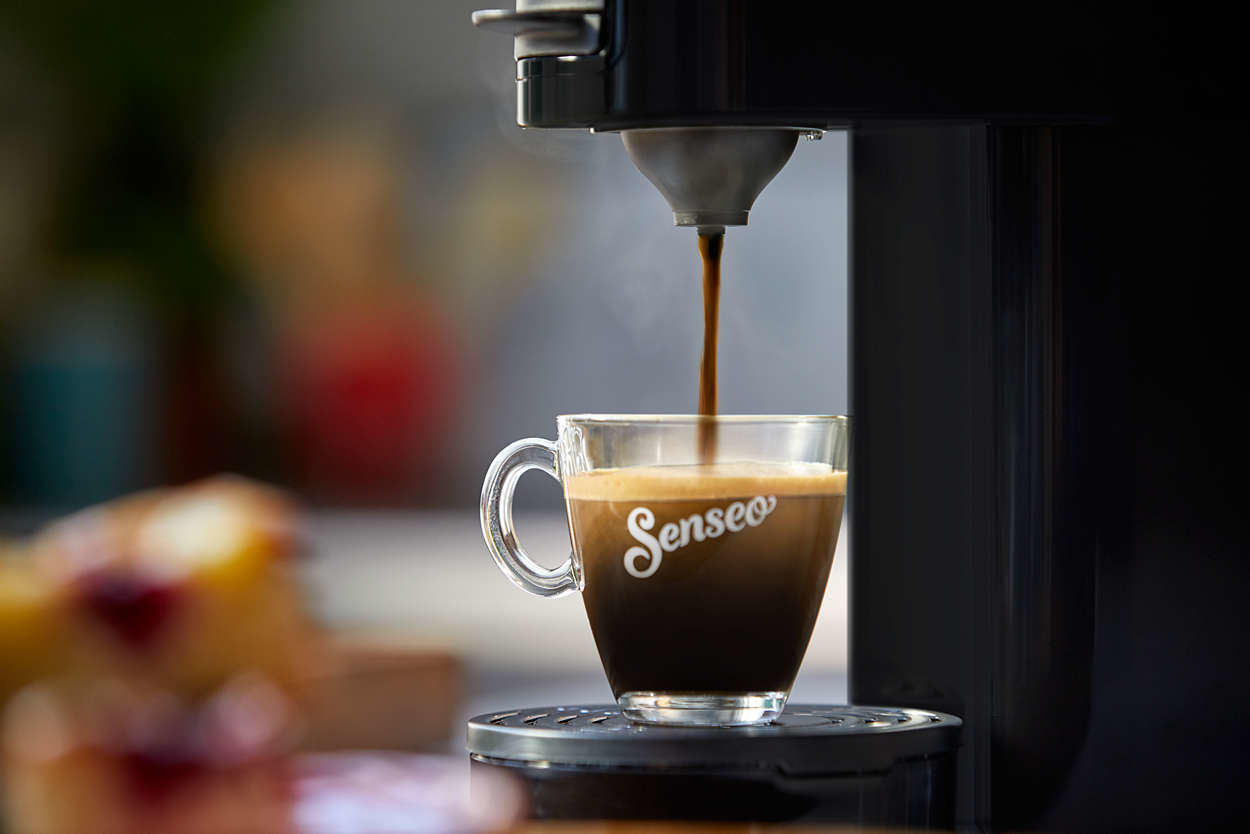 Nahaufnahme des Brühkaffees, wobei Kaffee in eine durchsichtige Glastasse gegossen wird.