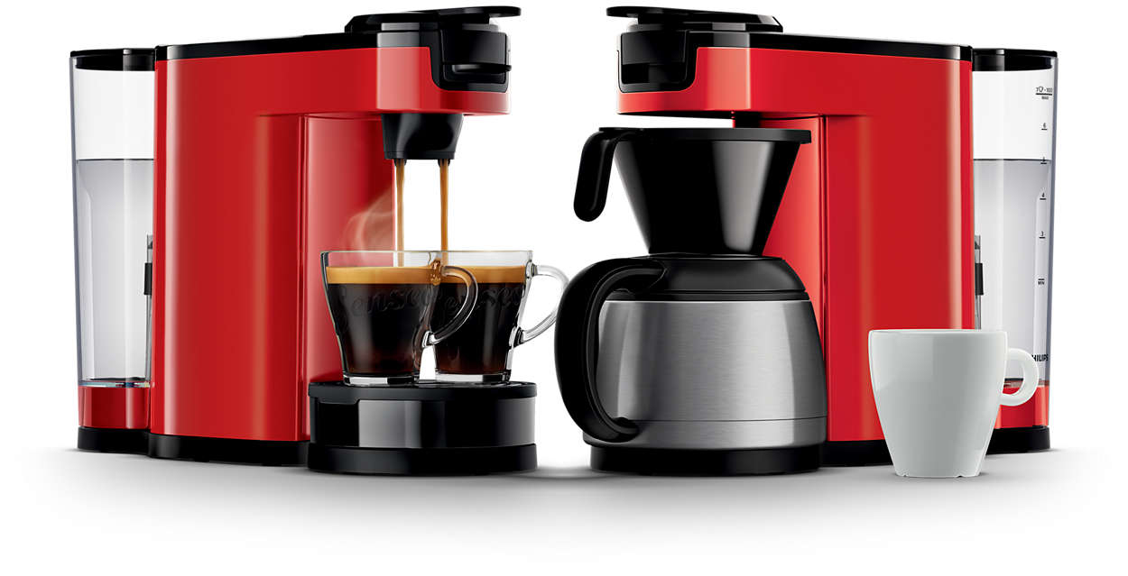 Twee rode koffiezetapparaten, één die koffie zet, met een witte mok in de buurt.