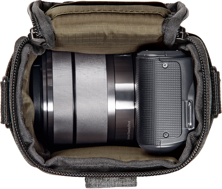 Camera in een cameratas. De camera is zilverkleurig. Donkergrijze tas, binnenin groen materiaal.