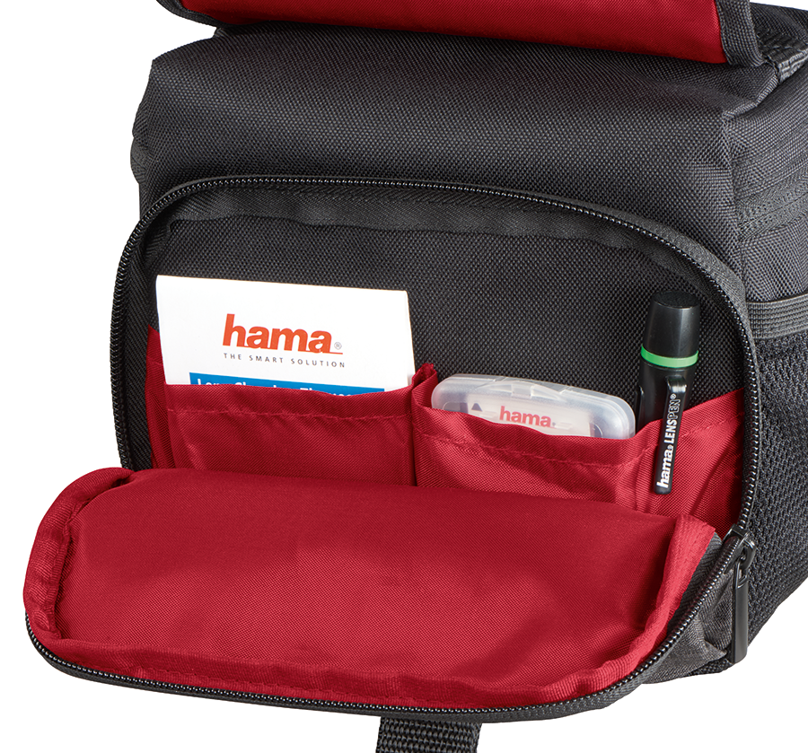Open camera bag revealing pockets with cards and a flashlight. Red interior contrasts with black exterior.