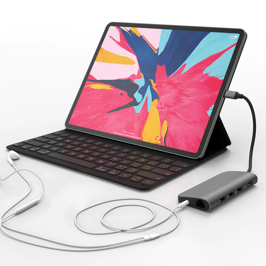 Tableta con teclado y concentrador, conectada a auriculares. La pantalla muestra ilustraciones coloridas.