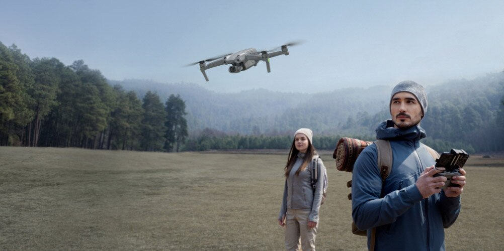 Ludzie z dronem latającym w leśnym krajobrazie.