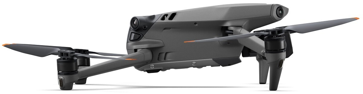 Szary dron z kamerą i śmigłami, widok z boku na białym tle.