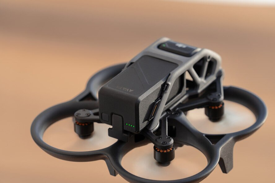 Czarny dron z czterema śmigłami, w rozmytym otoczeniu zewnętrznym.
