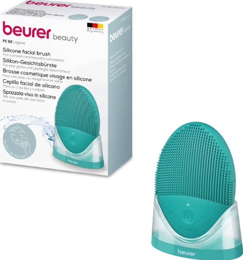 Une brosse visage turquoise avec un socle de chargement et une boîte du produit.