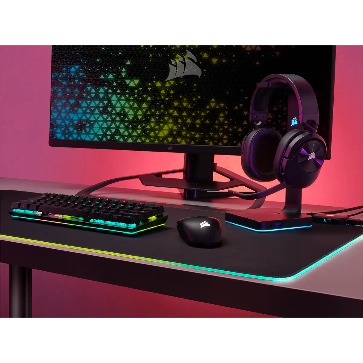 Játékbeállítás billentyűzettel, egérrel, fejhallgatóval és monitorral. A beállítás egy asztalon van RGB világítással.