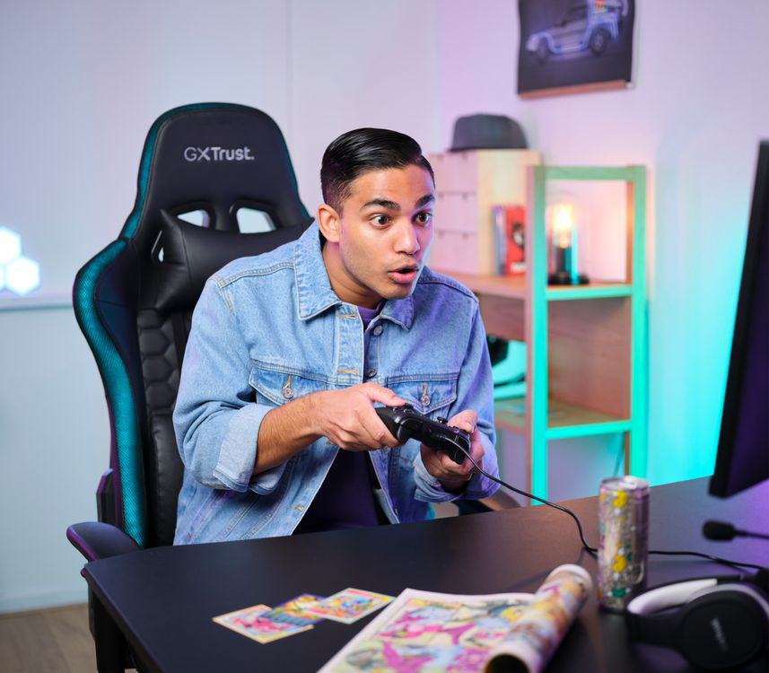 Egy fiatalember izgatottan játszik videojátékot, gamer székben ülve.