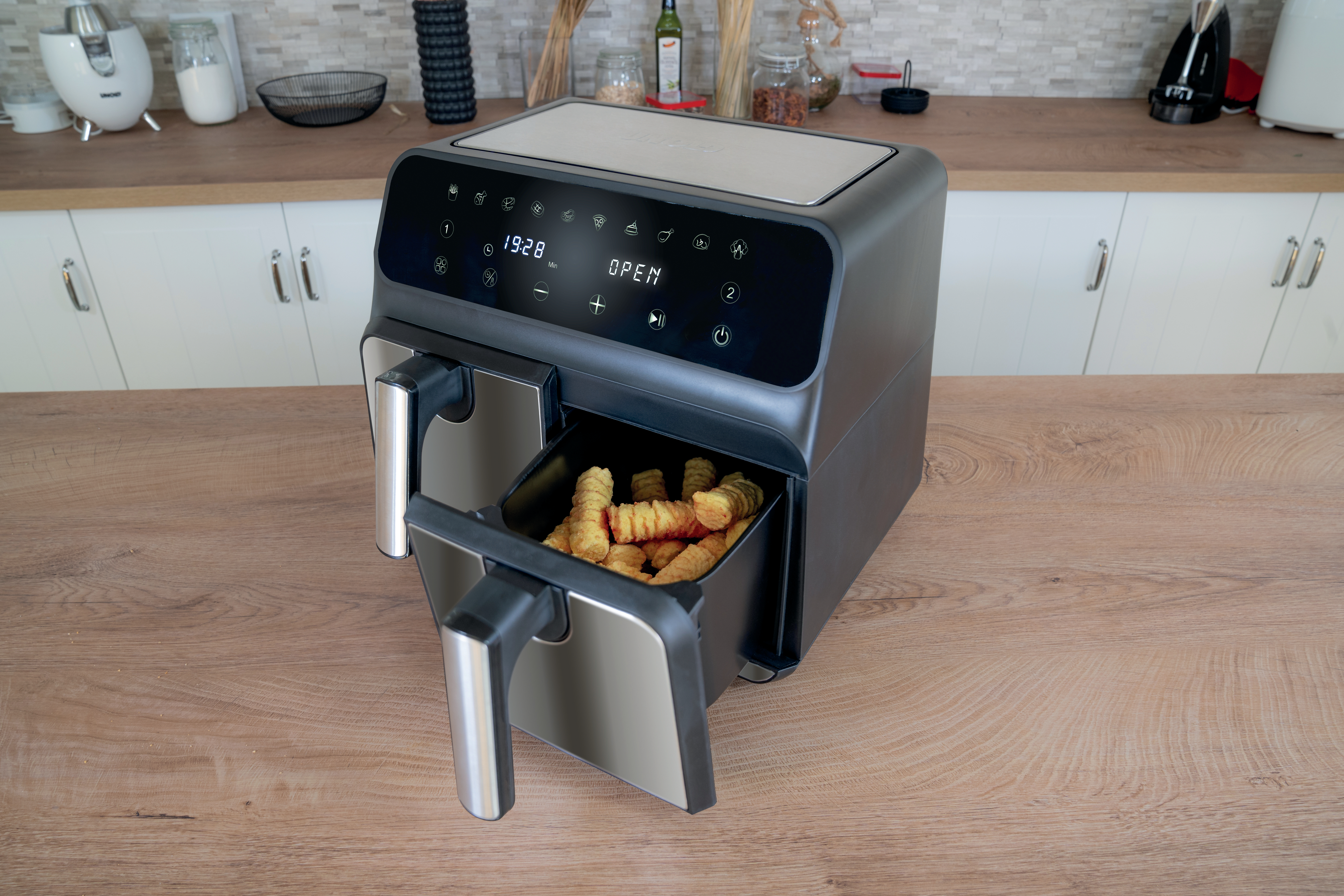 Schwarze Heißluftfritteuse mit offener Schublade mit Pommes auf Holztisch.