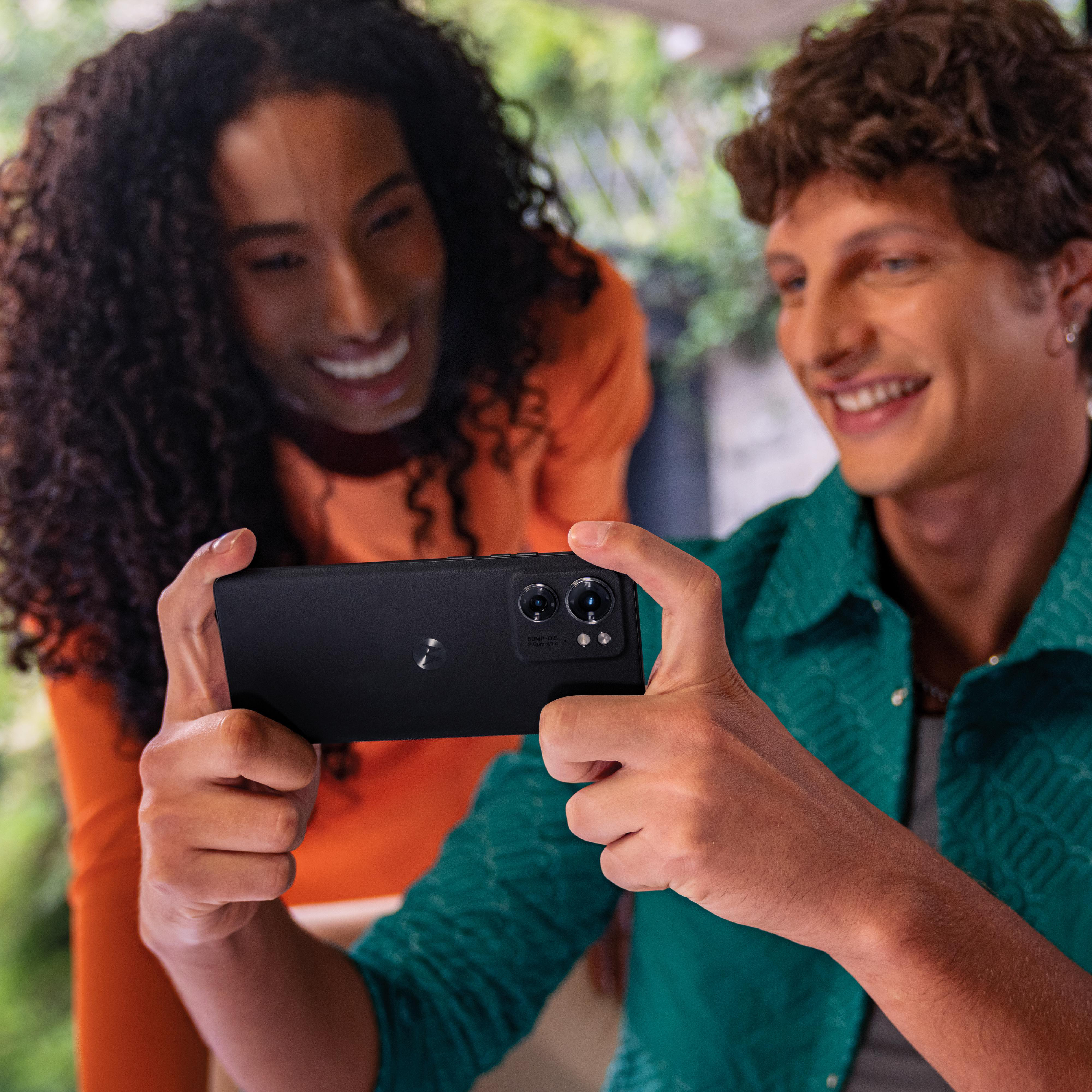 Zwei Personen betrachten ein schwarzes Smartphone, das von einem Mann gehalten wird.