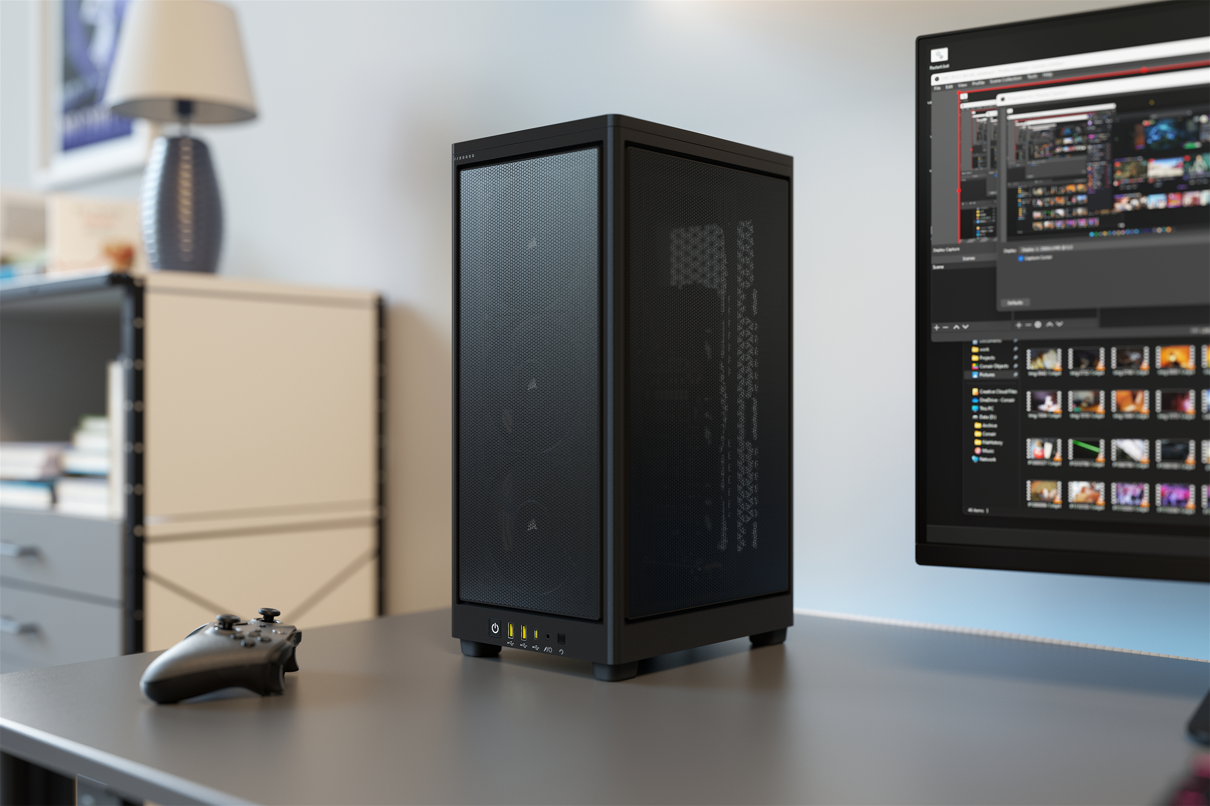 Ein schwarzes Computergehäuse steht auf einem Schreibtisch mit einem Monitor und einem Gamecontroller in der Nähe.